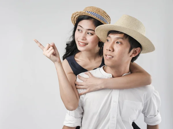 Счастливая азиатская пара в шляпе и кататься на спине на белом фоне — стоковое фото