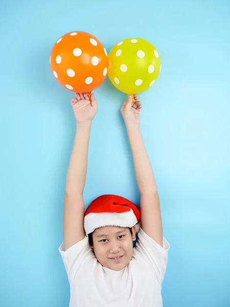 Asiatisk preteen pojke klädd i Santa hatt hålla ballonger med blå b — Stockfoto