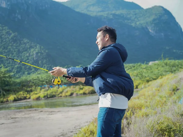 Asiatischer Mann angelt mit Naturhintergrund, Lifestylekonzept. — Stockfoto
