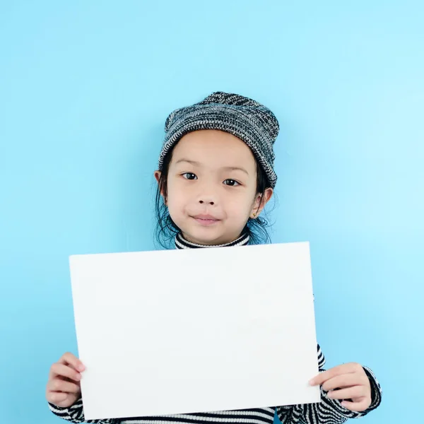 Asian girl in winter costume holding white blank paper on blue b — Stock Photo, Image