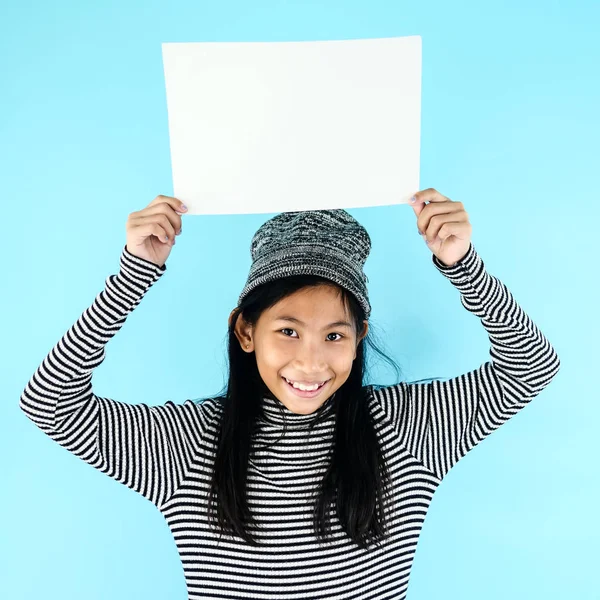 Asiatisk tjej i vinter kostym hålla vitt blankt papper på blå b — Stockfoto