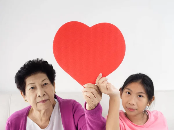 Asian senior woman holding red heart shape with her granddaughte — Stock Photo, Image