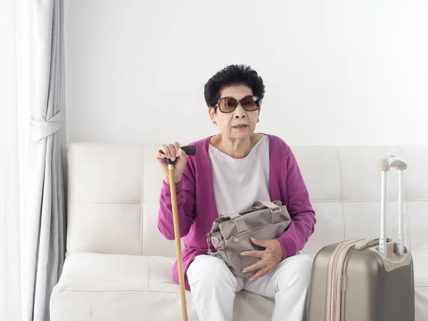 여행 가방을 들고 집에 앉아 있는 아시아 여성 — 스톡 사진