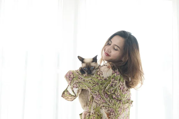 笑顔アジアの女性保持彼女の猫とともに窓の光に家. — ストック写真