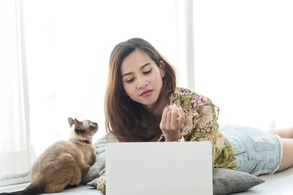 Felice donna asiatica utilizzando tablet sul pavimento con il suo gatto vicino alla finestra — Foto Stock