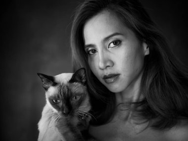 Güzel bir Asyalı kadının portresi, kedisini siyah tutuyor ve...