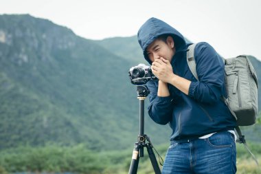 Asyalı fotoğrafçı, kış mevsiminde tripodla fotoğraf çekiyor.