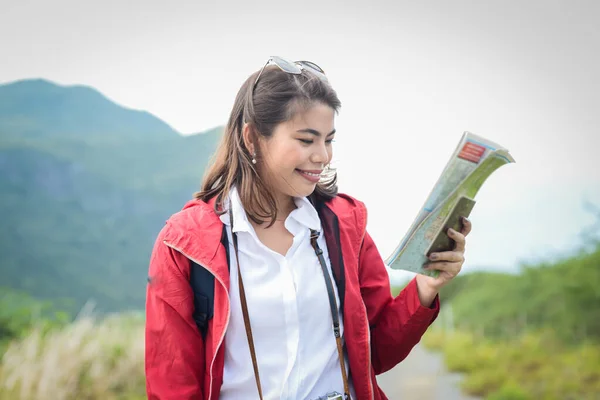 Asiatisk kvinna i röd jacka håller karta och letar efter hennes destin — Stockfoto
