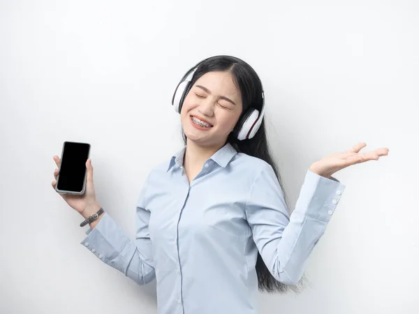 Heureuse femme asiatique en utilisant un téléphone intelligent et un casque écoutant de la musique — Photo