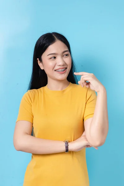 Glückliche asiatische Frau im gelben Kleid mit blauem Hintergrund. — Stockfoto