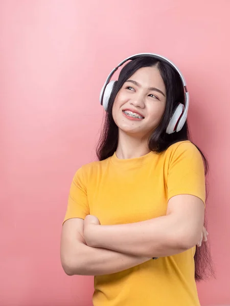 Happy Asian woman in yellow dress using headphone with pink back — Stock Photo, Image