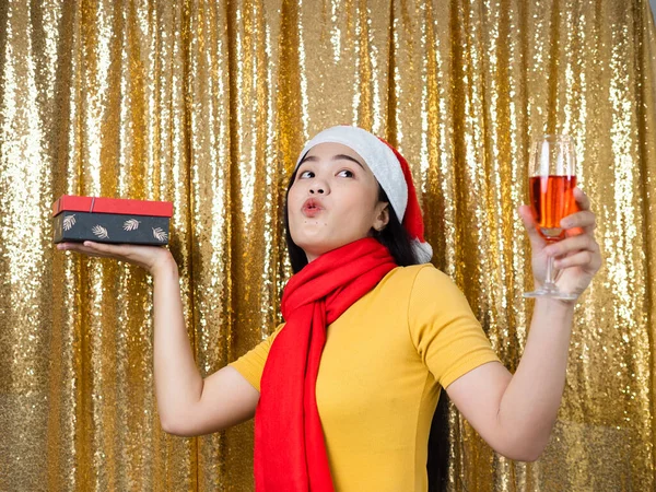 Happy Asian woman with red Santa hat and drinking red wine on go