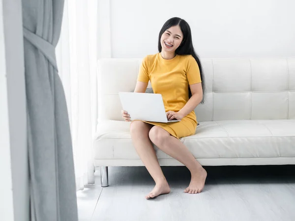Азиатская женщина в желтом платье с ноутбуком дома, conc lifestyle — стоковое фото
