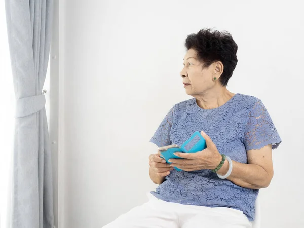 Aziatische senior vrouw met behulp van smart phone thuis. — Stockfoto