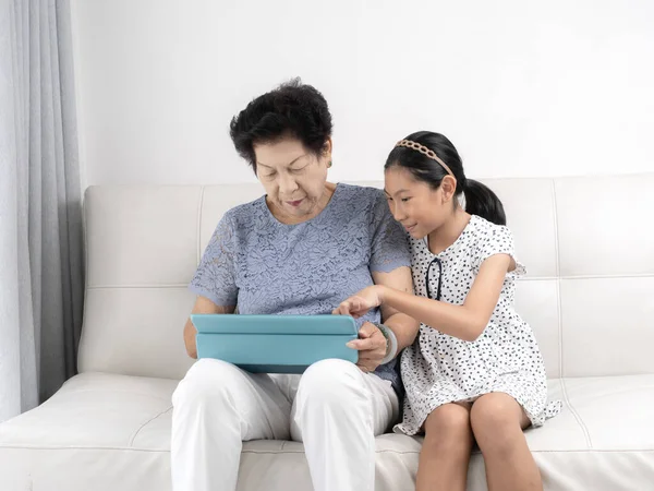 Asian senior woman and girl using tablet at home, lifestyle conc