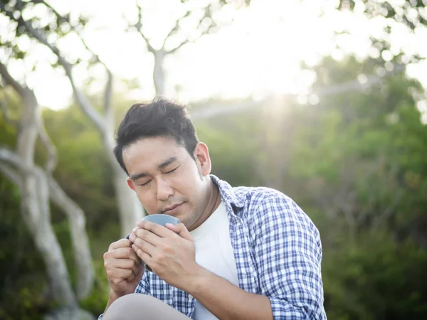Asiático homem segurando xícara de café com natureza ao ar livre, estilo de vida conc — Fotografia de Stock