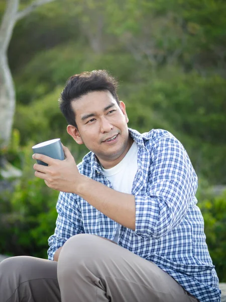 Asijský muž drží šálek kávy s přírodou venku, životní styl conc — Stock fotografie