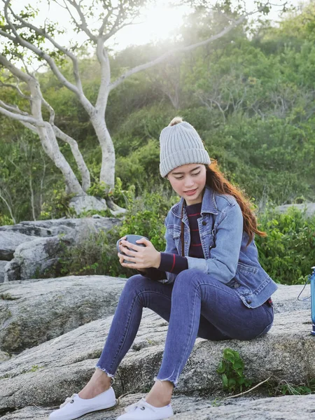 Mujer asiática feliz sosteniendo taza de café con sol destello al aire libre . — Foto de Stock