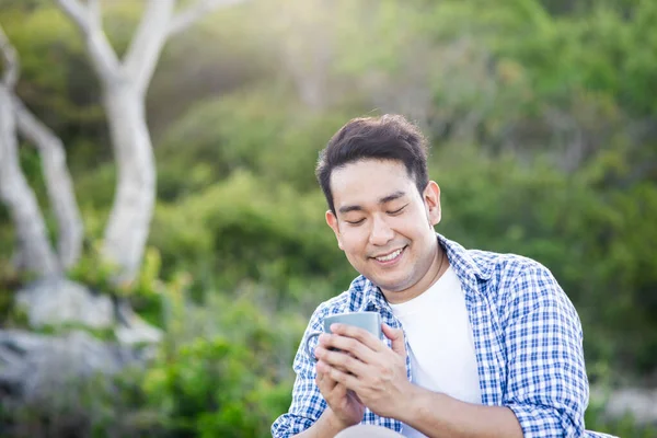 Asiático homem segurando xícara de café com natureza ao ar livre, estilo de vida conc — Fotografia de Stock