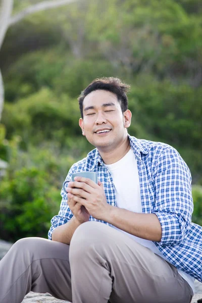 Asijský muž drží šálek kávy s přírodou venku, životní styl conc — Stock fotografie