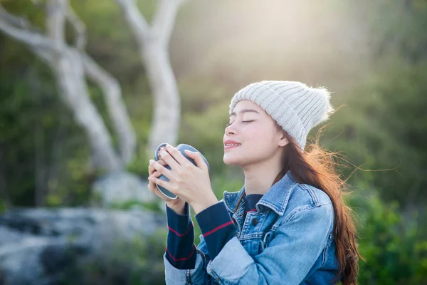 Mujer asiática feliz sosteniendo taza de café con fondo de la naturaleza, leva —  Fotos de Stock