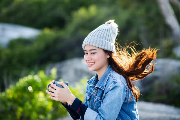 Glücklich asiatische Frau hält Kaffeebecher mit Natur Hintergrund Nocken — Stockfoto