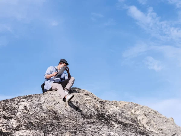 Asiatisk turist sitter på klippan och ser karta med blå himmel — Stockfoto