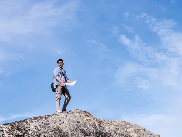 Asiatisk turist står på klippan och ser karta med blå himmel — Stockfoto
