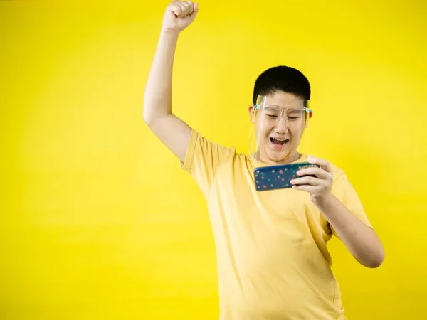 가리개를 착용하고 노란색 스마트폰으로 게임을 아시아 새로운 — 스톡 사진
