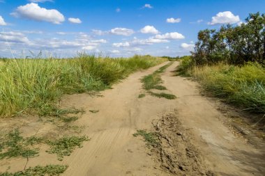Mavi gökyüzü ve bulutların arka planda bozkırda Kir yol.