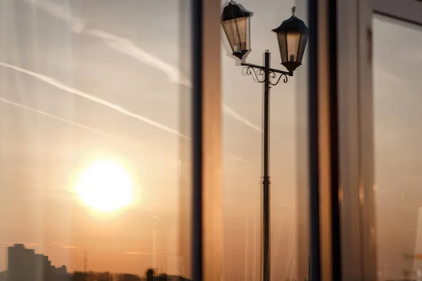 Reflection of the sunset and lanterns in the window of the embankment cafe