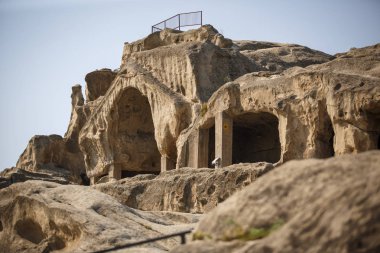 Georgia 'daki antik taş mağara şehri Uplistsikhe. Kahverengi taş, kavurucu güneşin altında çöldeki harabeler ve mağaralar. Taş evler, kilise, antik manzaralı sokaklar..