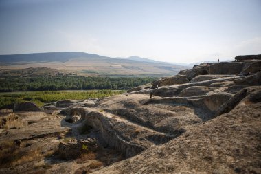 Georgia 'daki antik taş mağara şehri Uplistsikhe. Kahverengi taş, kavurucu güneşin altında çöldeki harabeler ve mağaralar. Taş evler, kilise, antik manzaralı sokaklar..