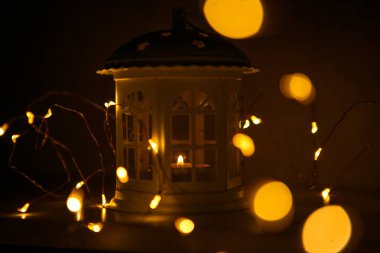 Parlayan Fener penceresi olan bir ev şeklinde sarı yaktı. Yeni yıl için festival iç dekorasyon. Çelenk ışıklar ve parlayan lamba, çatıda yıldız iç mumlar