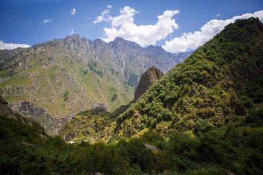 Georgia Dağları 'nda şafak vakti. Güneşin soğuk ışığı, yeşil vadinin aydınlatılması, uzun boylu karanlık dağların arkasında akarsu.
