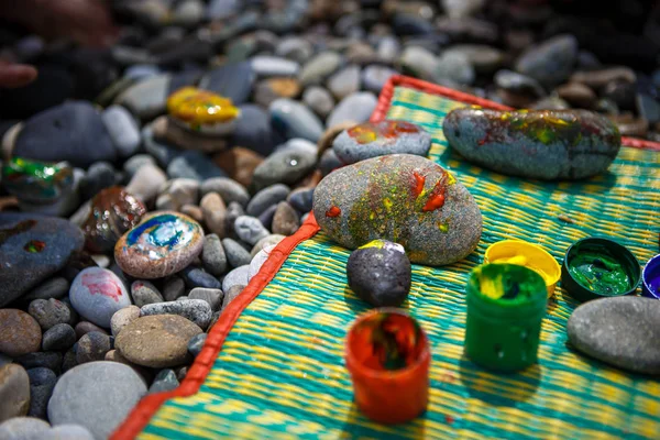 Children\'s entertainment on a pebble beach-paint stones. Painted with finger paints stones and jars of paint, leisure for the child, children\'s creativity.