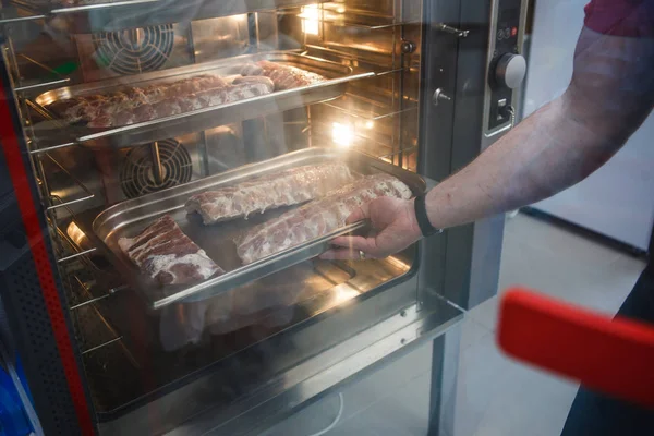 烟熏肉制品在烤箱烟囱里 一个男人拿着一盘烟熏肉制品 — 图库照片