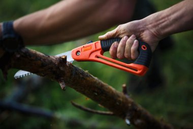 Küçük bir turist el kullanarak yürüyüş gördüm. Erkek el odun katlama testere turuncu testere