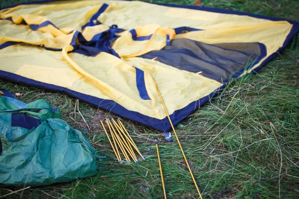 组装和安装旅游帐篷的过程 弧形帐篷和桩子躺在拉伸帐篷旁边的地面上 — 图库照片