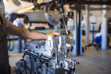 Elinde bir alet ile mekanik makinenin motoru tamir. Servis istasyonunda çalışma süreci