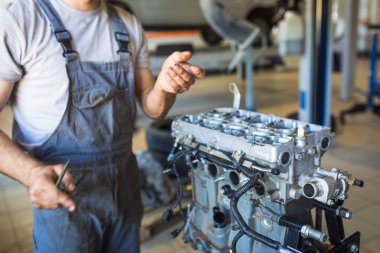 Elinde bir alet ile mekanik makinenin motoru tamir. Servis istasyonunda çalışma süreci