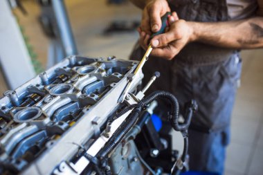 Elinde bir alet ile mekanik makinenin motoru tamir. Servis istasyonunda çalışma süreci