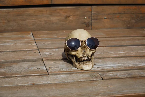 Ahşap Arka Planda Güneş Gözlüklü Bir Insan Kafatası Parlak Işıkla — Stok fotoğraf
