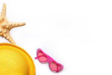 Güneş koruması için plaj aksesuarları: çocukların sarı hasır şapkaları, beyaz arka planda pembe kalp şeklinde gözlükler. Metin için alanı olan bir düzen. Yolculuğa ve deniz tatillerine hazırım.