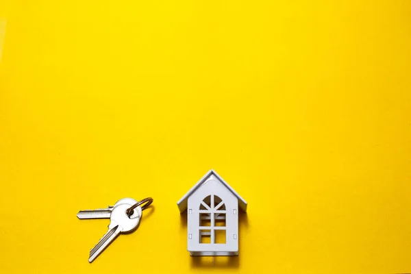 黄色の背景に白い木造の家のシンボルとキー コテージ建設の概念は レイアウトや設計 建築計画は 新しい家に移動し 不動産業者代理店 ターンキービジネス テキストのためのスペース フラット — ストック写真