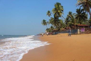 Goa, Hindistan-7 Ocak 2017. İnsanlar sahil şeridi boyunca Sinquerim 'de yürüyor. Turistler ve yerel halk, kumlu sahilde bir grup Hintli.