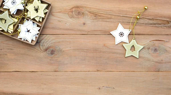 Christmas flatlay on a wooden background in rustic style: decorations made of wood in the shape of a star, spruce. Stencils in the shape of a deer, snowflakes. New year, home comfort. Space for text
