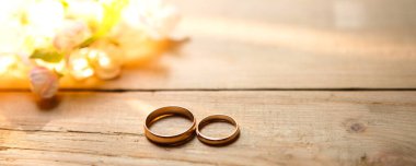 Two gold rings on a wooden background with white Apple blossoms. Wedding in eco-style, rustic. Couple in love, ceremony and registration, details, bride's fees, groom's morning. Space for text. flatly. clipart