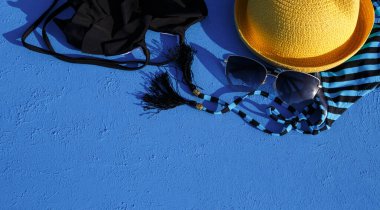 Mavi arka planda bir plaj tatili için kadın aksesuarları. Denize yolculuk konsepti, rahatlama, yüzme, ultraviyole koruma, bronzlaşma. Turizm ve seyahat acentesi. Mesaj için yer. Çerçeve. Düz Yatay