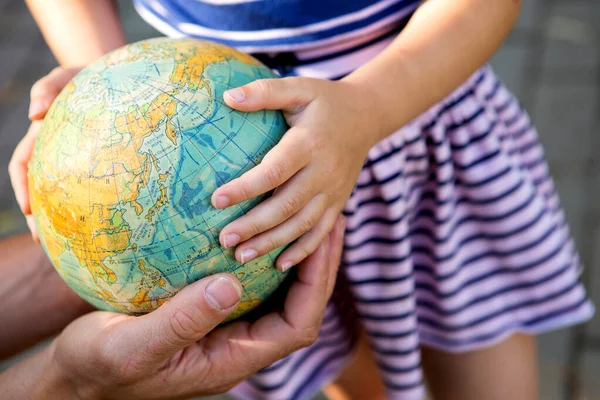 Kaluga, Russia-June 23, 2020. Dad shows his daughter the finger of the country on the globe in Russian. A girl from elementary school is studying the planet. Back to school, father's day.